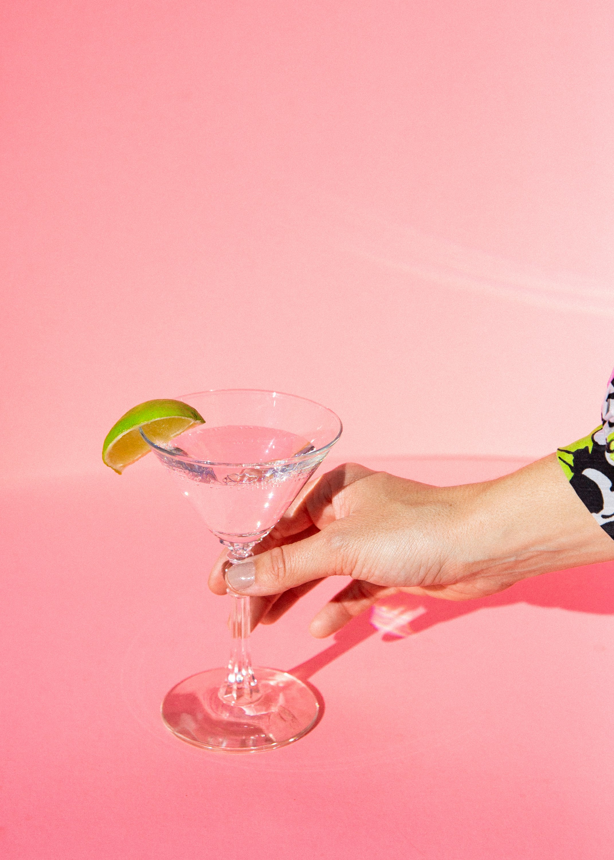 person holding clear cocktail glass with green straw